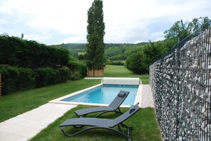 Relax by the serene pool surrounded by lush greenery and a picturesque natural landscape.