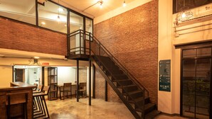 Um hall amplo com parede de tijolos, escada e área de bar.