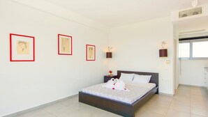 Un dormitorio moderno con una cama grande, una mesita de noche con lámpara y tres cuadros enmarcados en la pared.