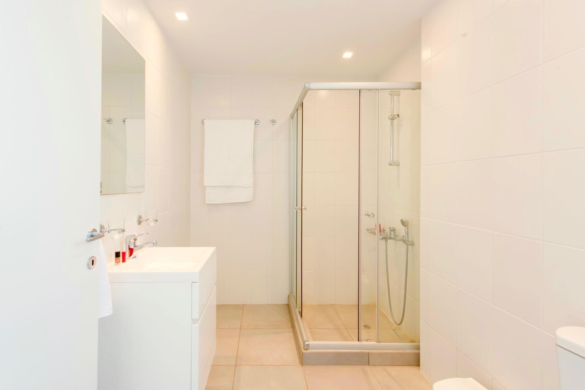 A modern bathroom with a glass-enclosed shower, a white sink with a mirror, and a toilet.