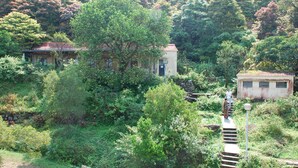 Ein traditionelles Gebäude, umgeben von üppiger Vegetation und einer Steinmauer.