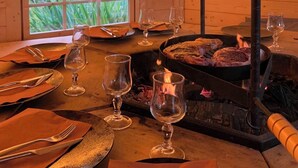 Un comedor con una parrilla, mesa dispuesta con platos, cubiertos y copas de vino.