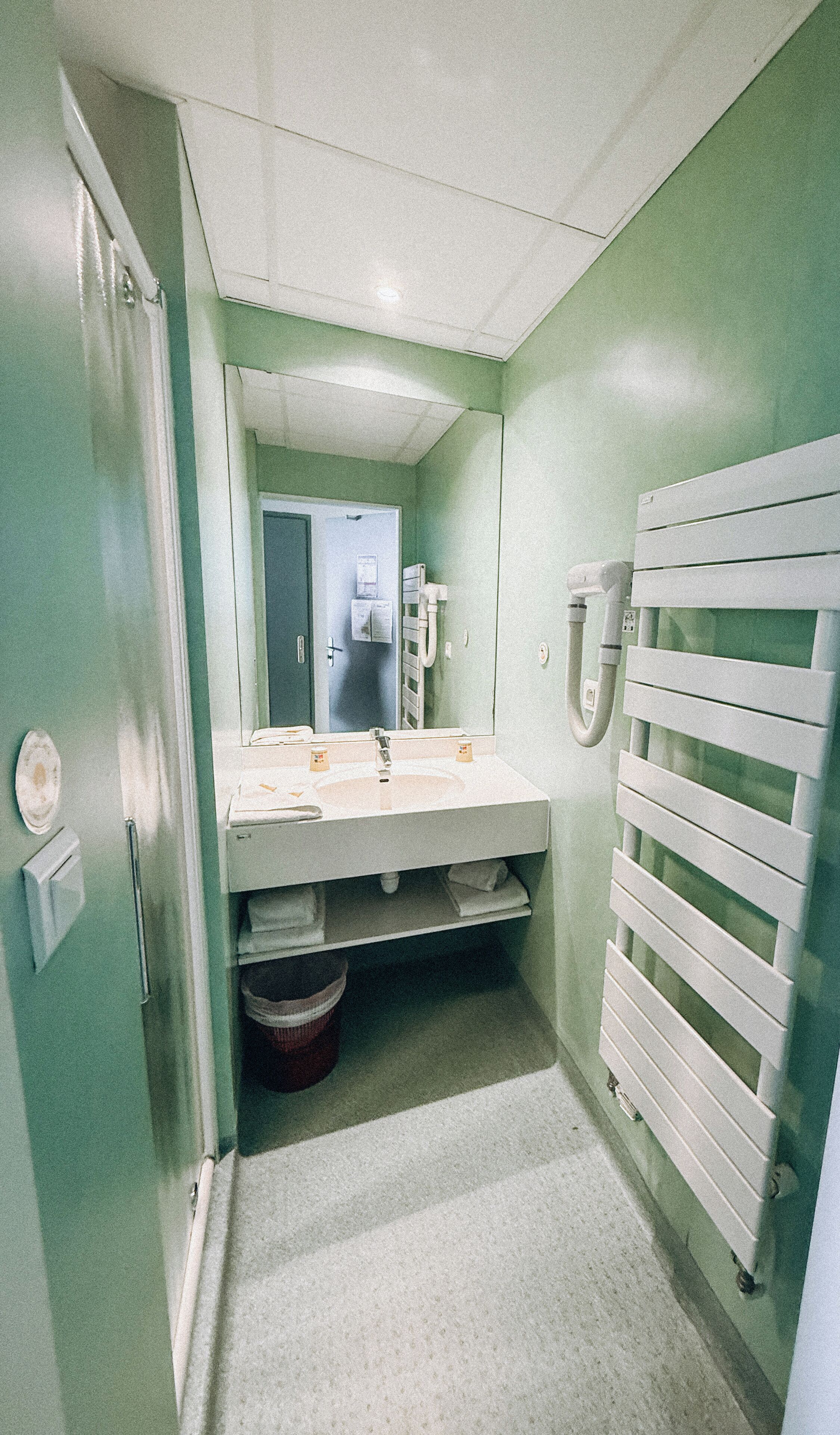 A small bathroom with a sink, mirror, and towel rack.
