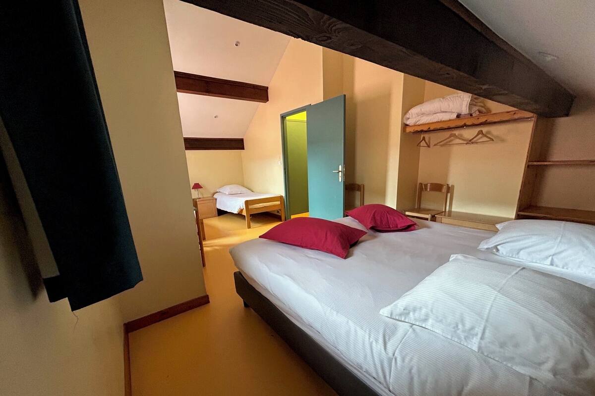 A bedroom with a bed, two pillows, a wooden headboard, a door, and a chair.