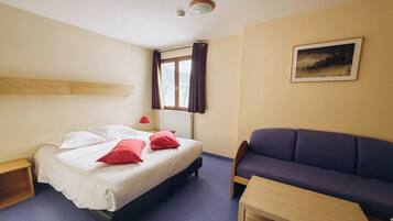 Une chambre d’hôtel avec un lit, un canapé, une table et une fenêtre avec des rideaux.