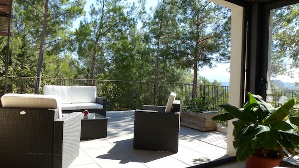 A balcony with outdoor furniture, a potted plant, and a view of tall trees. - CONTEMPORARY VILLA IN PROVENCE CAMPAIGN, AIX EN PROVENCE, AUBAGNE, MARSEILL (Peypin)