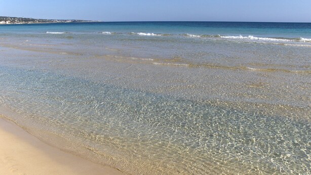 Una spiaggia con acque cristalline e una costa sabbiosa.