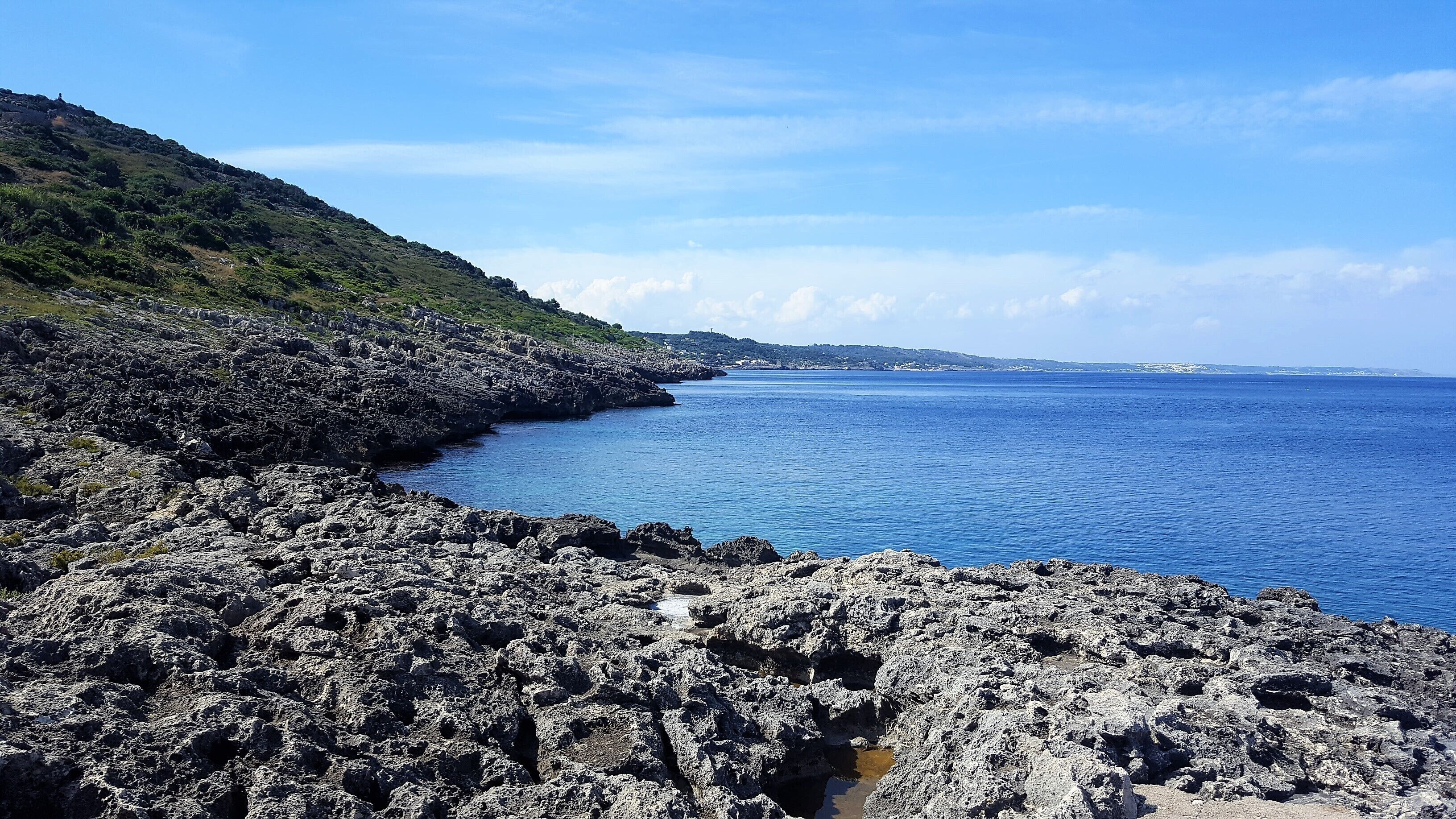 A rocky coastline with a clear view of the sea and distant land.
