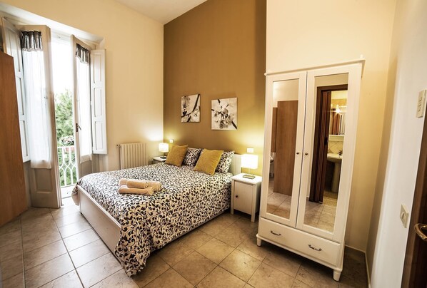 A bedroom with a bed, bedside tables, a wardrobe, and artwork on the wall. - B&B Germinario (Trani)