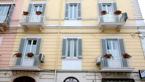 Un edificio de varios pisos con balcones, cada uno adornado con macetas.