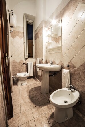 A bathroom with a toilet, bidet, sink, and bidet tub. - B&B Germinario (Trani)