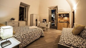 Un dormitorio con dos camas, un escritorio y una silla. Hay una ventana y una puerta que da a un baño.