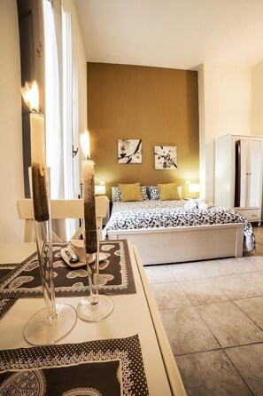 A bedroom with a bed, bedside tables, a wardrobe, and a window with curtains. - B&B Germinario (Trani)