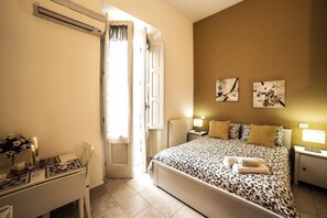 A bedroom with a bed, bedside tables, a desk with a chair, and a window with curtains. - B&B Germinario (Trani)