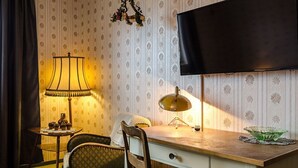 A room with a desk, two chairs, a lamp, a television, and a patterned wallpaper. - Hotel Rosenhof (Isenbuttel)