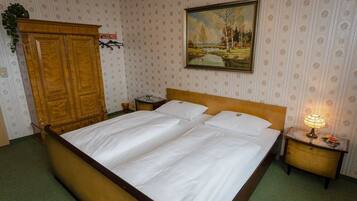 A bedroom with a wooden bed, a nightstand with a lamp, a wardrobe, and a painting on the wall.