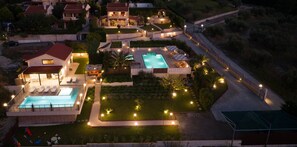 A residential property with a swimming pool, outdoor seating area, and well-lit pathways.