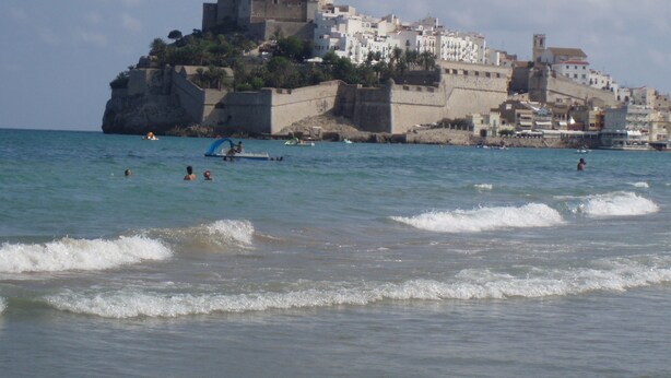 A coastal town with a prominent castle-like structure on a cliff overlooking the sea.