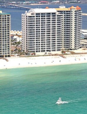 Ein Küstenhotel mit mehreren Hochhäusern, einem Strand und einem Pier im Hintergrund.