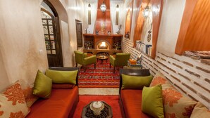 A cozy lounge area with a fireplace, seating, and a patterned rug. - RIAD DAR YEMA (marrakech)