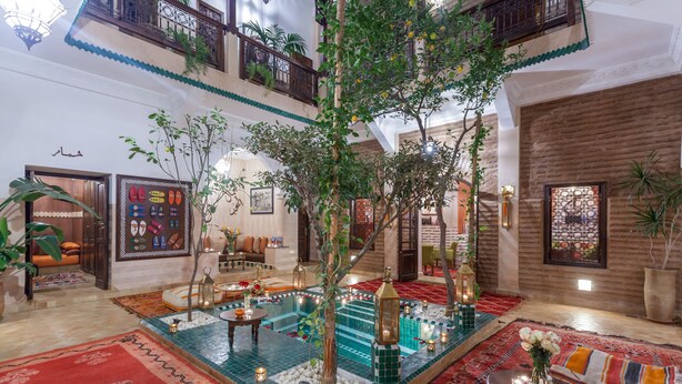 A spacious indoor area with a central pool, surrounded by colorful rugs and seating areas. - RIAD DAR YEMA (marrakech)