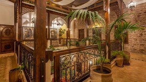 A multi-level interior with wooden railings, potted plants, and stone walls. - RIAD DAR YEMA (marrakech)