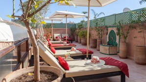 A rooftop lounge area with sun loungers, umbrellas, and potted plants. - RIAD DAR YEMA (marrakech)