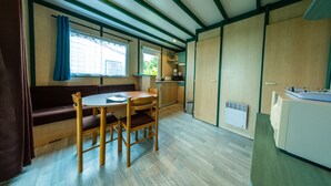A compact kitchen with a dining area, a built-in stove, and a window with curtains. - Chalet with terrace in the countryside, ideal quiet location. (Tauriers)
