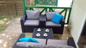 A wicker outdoor seating area with cushions and a table set with cups. - Chalet with terrace in the countryside, ideal quiet location. (Tauriers)
