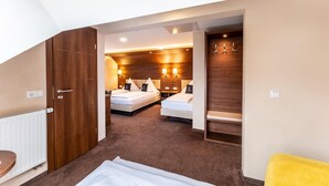 Moderni hotellihuone, jossa on kaksi sänkyä, puiset päätyosat ja pieni oleskelualue.
