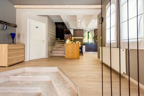 A modern kitchen with a central island, a staircase leading to an upper level, and a view of a dining area. - Villa Murtal (Rethymno)