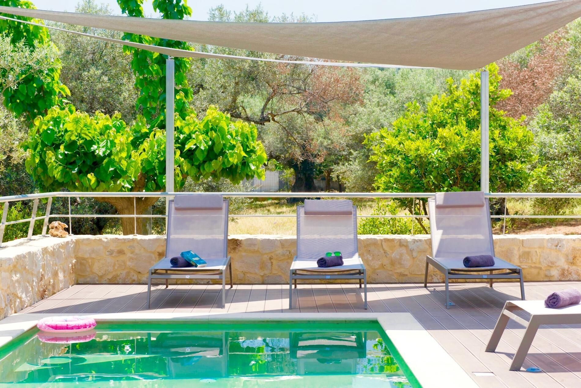 Una piscina al aire libre, sombrillas, sillones reclinables de piscina