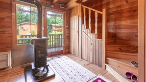 Una baita di legno con camino, una scala in legno e vista sull'esterno.