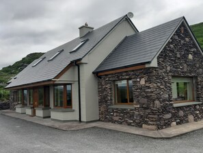 A two-story house with a stone facade, a sloped roof, and a chimney. - 5* holiday home overlooking Lough Currane Free Wifi Near Hogs Head Golf Course (Waterville)
