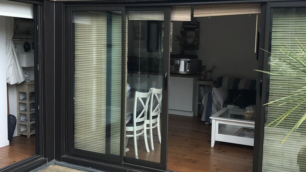 Un interior moderno con una puerta de cristal corredera que da a un comedor, una cocina y un espacio de estar.