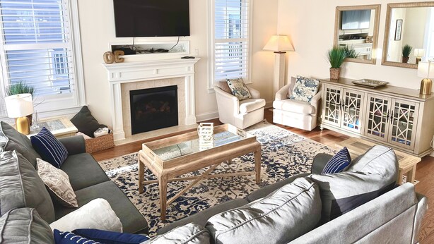 A living room with a fireplace, a television, a ceiling fan, and a large window. - STEPS TO BEACH & BOARDWALK. 5BR/3BATH. Private Elevator! (Ocean City)