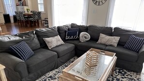 A modern living room with a sectional sofa, patterned rug, and a glass coffee table. - STEPS TO BEACH & BOARDWALK. 5BR/3BATH. Private Elevator! (Ocean City)