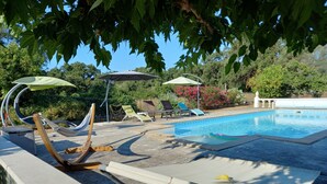 A poolside area with lounge chairs, umbrellas, and a hammock. - House, pool, haven of peace   (Prunelli-di-Fiumorbo)