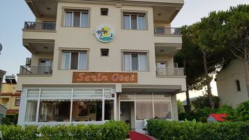 Hotel llamado "Serin Otel" con un letrero, varios balcones y una alfombra roja que lleva a la entrada.
