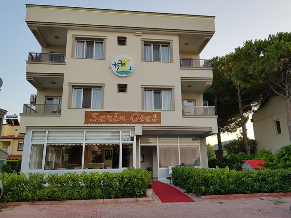 A hotel named "Serin Otel" with a signboard, multiple balconies, and a red carpet leading to the entrance. - Serin Otel (Urla)