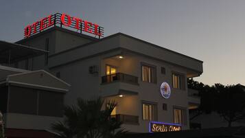 Un hotel con un llamativo letrero 'OTEL' en el techo, un balcón con barandilla y un cartel de 'Seren Hotel' en la fachada del edificio.