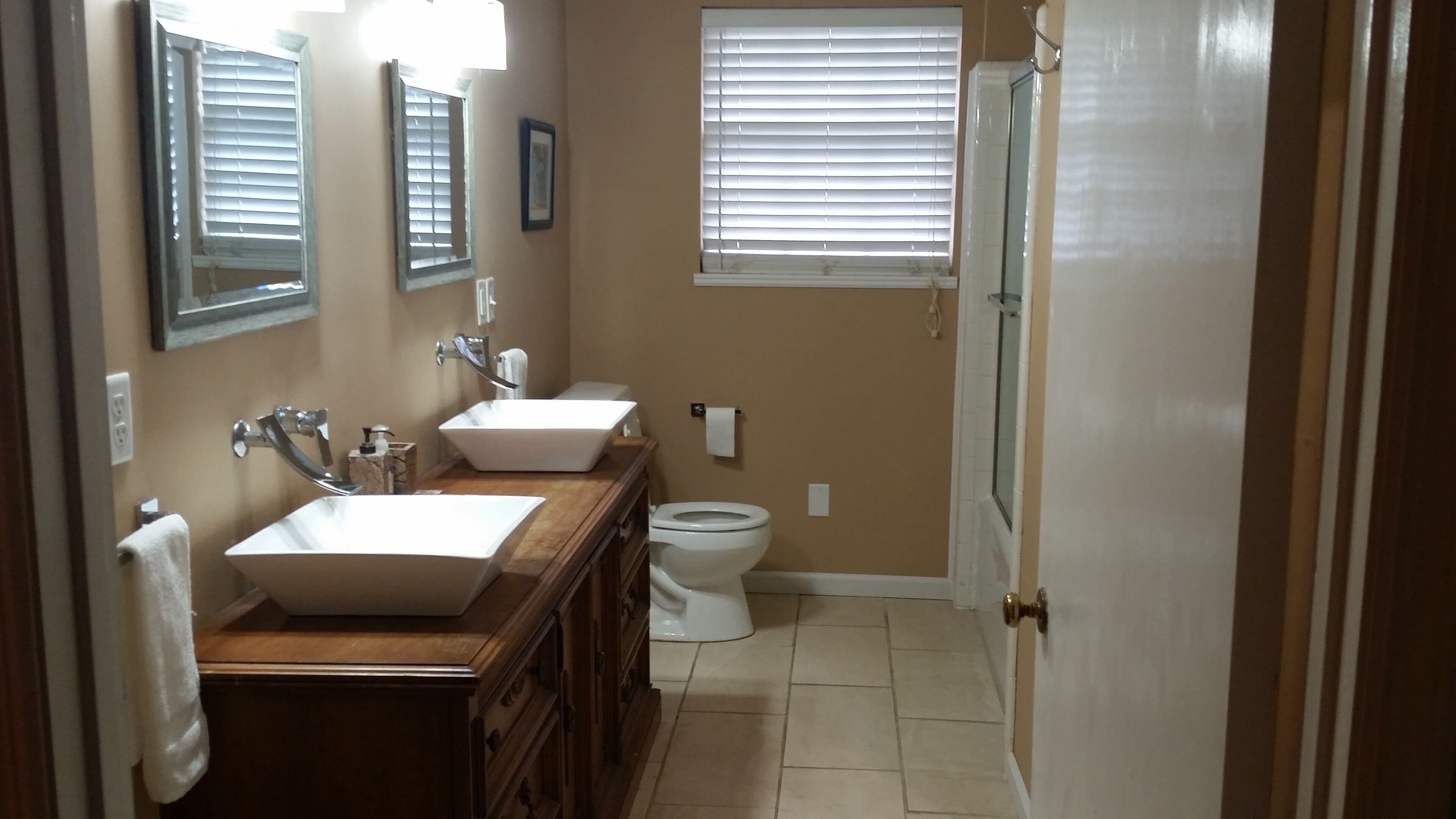 A bathroom with two sinks, a toilet, and a shower.
