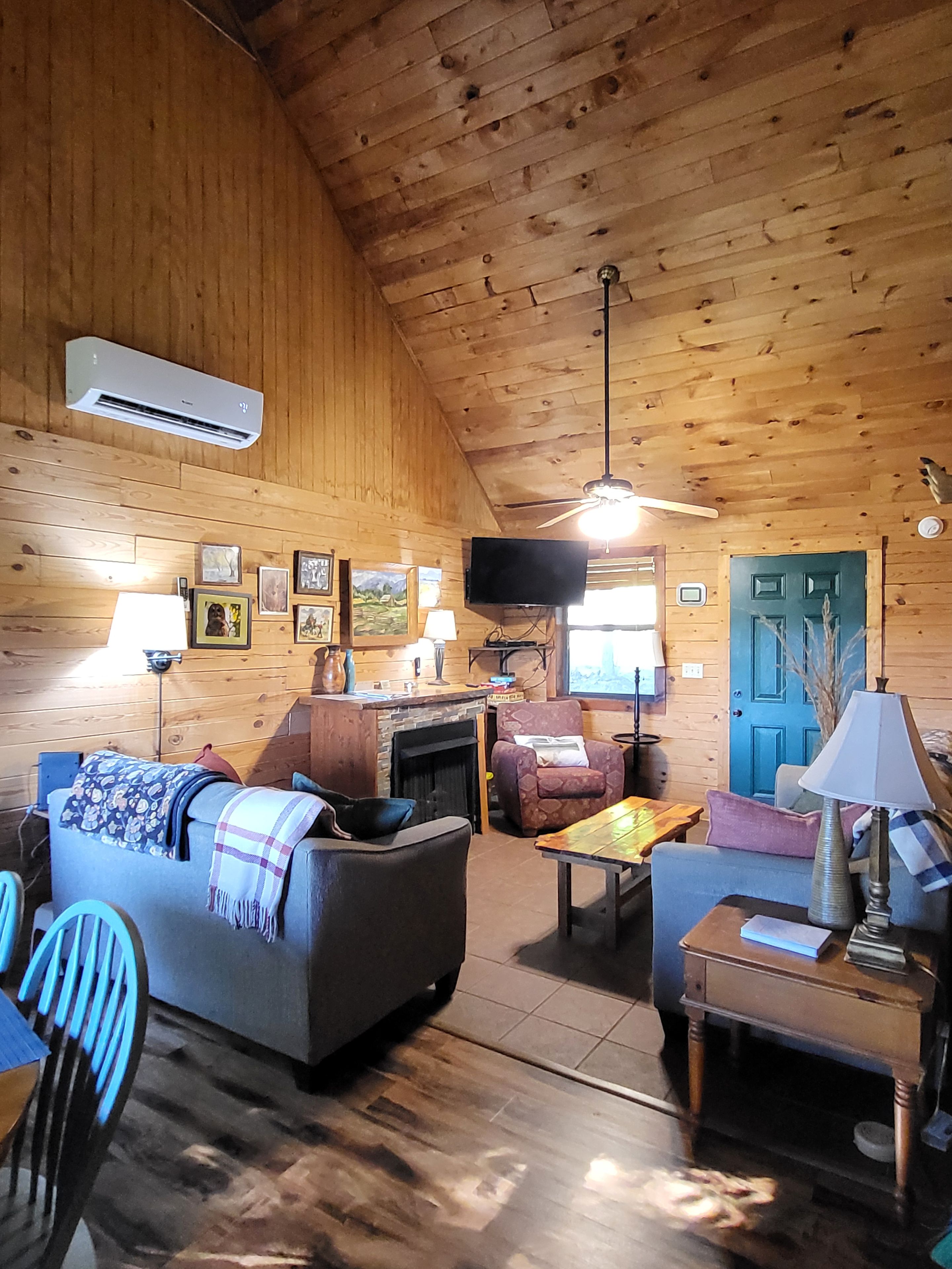 L’intérieur d’un chalet accueillant, avec un plafond en bois, une cheminée, un canapé, un téléviseur et une table à manger.