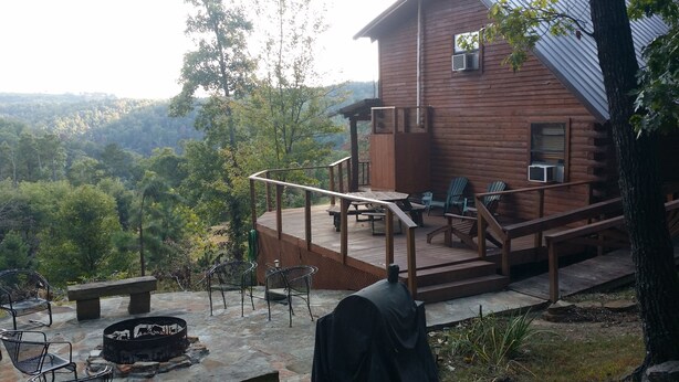 Una cabaña de madera con terraza, mobiliario exterior y una chimenea.