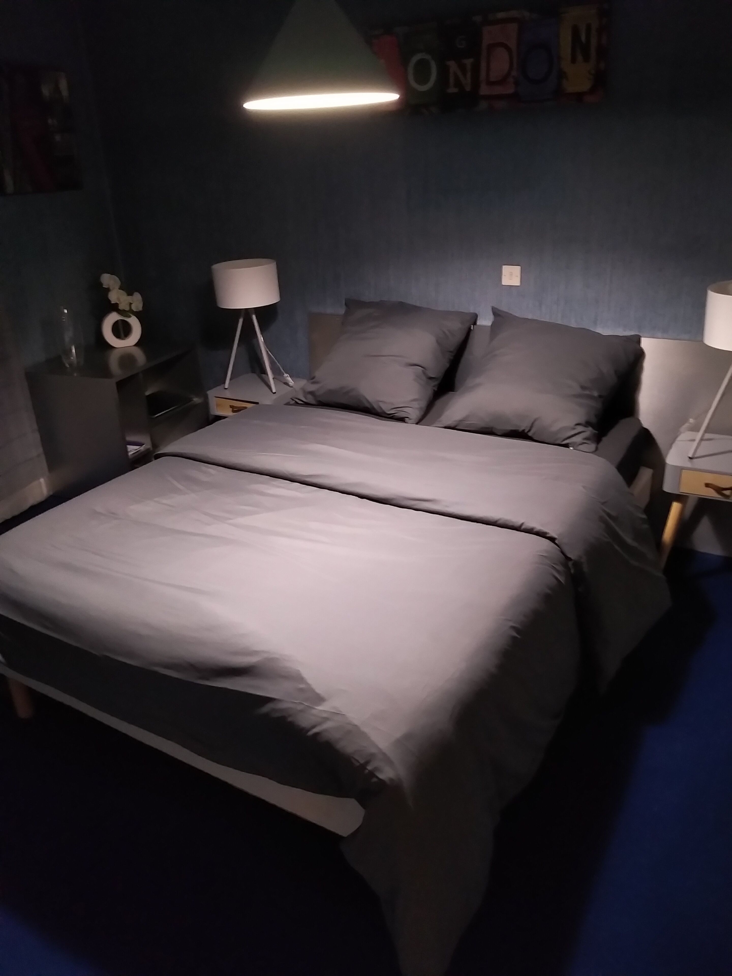 Une chambre à coucher avec un lit, deux tables de chevet et une lampe fixée au mur.
