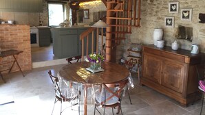 A rustic kitchen with a wooden staircase, a dining table with chairs, and a stone wall with framed pictures. - Authentic House of charm 4 stars magnificent view on castles (Beynac-Et-Cazenac)