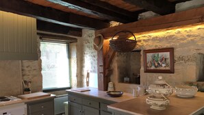 A rustic kitchen with wooden beams, a stone wall, and a window with blinds. - Authentic House of charm 4 stars magnificent view on castles (Beynac-Et-Cazenac)