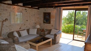 A cozy living room with wicker furniture, a glass coffee table, and a view of greenery outside. - Authentic House of charm 4 stars magnificent view on castles (Beynac-Et-Cazenac)