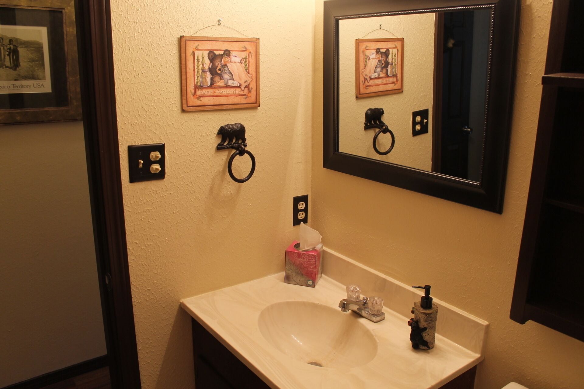 A bathroom with a sink, mirror, and framed pictures on the wall.