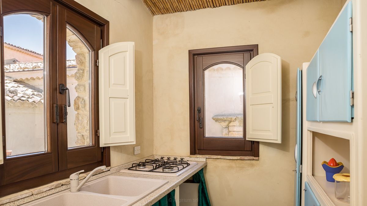 A compact kitchen with a gas stove, a sink, and a window with a view of the outside.